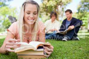 Girl lying while reading books in a park