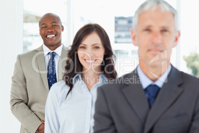 Young smiling employee standing upright and following his team