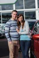 Couple holding tight while standing next to a car