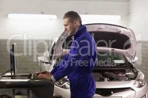 Mechanic standing while looking at a computer