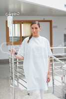 Female patient holding a drip stand in the corridor
