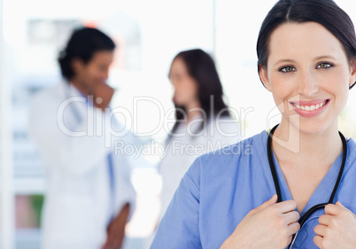 Confident nurse standing upright accompanied by her team in the