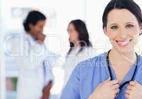 Confident nurse standing upright accompanied by her team in the