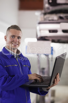 Smiling mechanic typing on a laptop