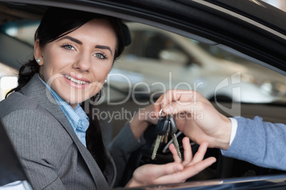 Smiling woman in a car receiving car keys