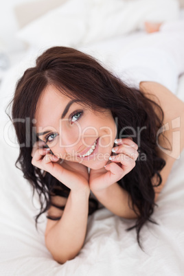 Joyful woman lying on her white quilt