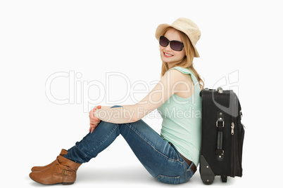 Woman wearing sunglasses while sitting near a suitcase