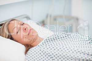 Woman lying on a bed while closing her eyes