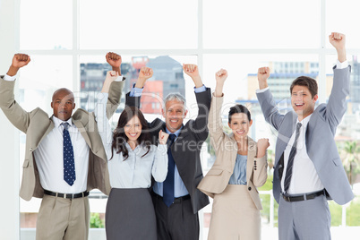 Smiling business team standing upright with arms raised in succe