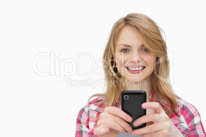 Smiling woman using a mobile phone while looking at camera