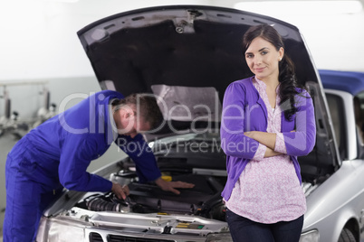 Woman leaning on a car next to a mechanic