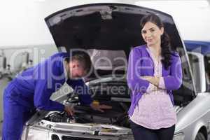 Woman leaning on a car next to a mechanic