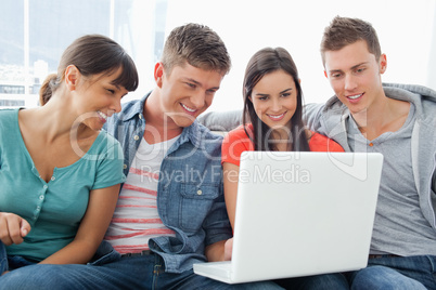 A smiling group of friends sitting around a laptop