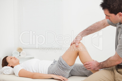 Brunette woman lying while a physiotherapist manipulates her leg