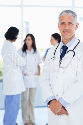 Mature doctor crossing his hands in front of his team