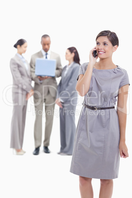 Businesswoman smiling on the phone with one arm along her body a
