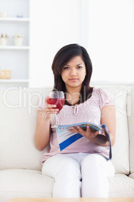Woman holding a red glass of wine and a magazine