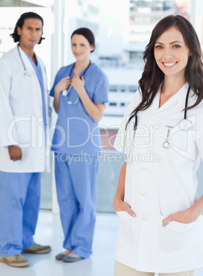 Smiling female doctor standing upright with her hands in her poc