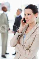 Businesswoman seriously talking on the phone with executives beh