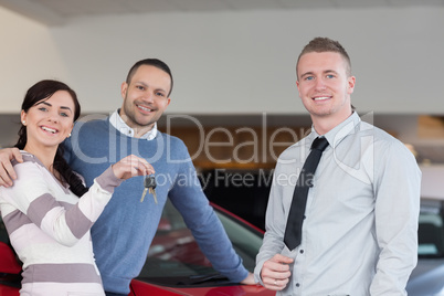 Salesman giving keys to an embracing couple