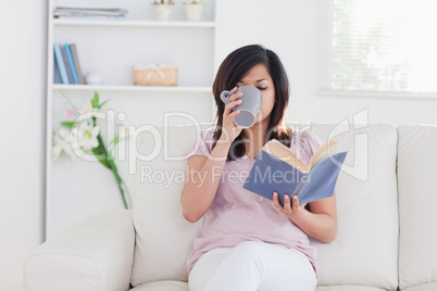 Woman holding a book and drinking