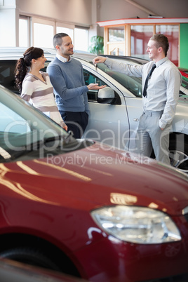 Smiling salesman giving keys to a happy couple