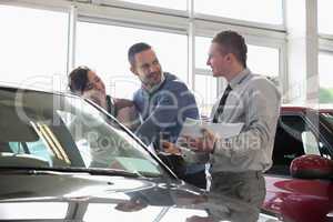 Salesman and a couple looking at a car
