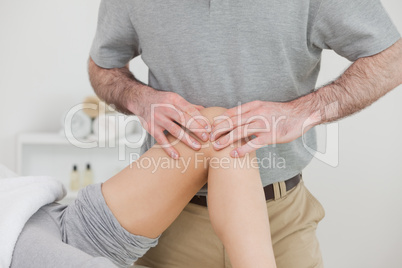 Woman lying with her legs folded while a man massaging her knee