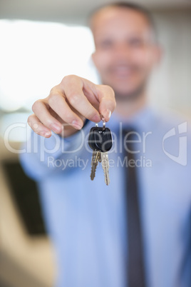 Salesman holding car keys by his fingertips