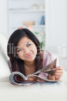 Woman resting on a couch while holding a magazine