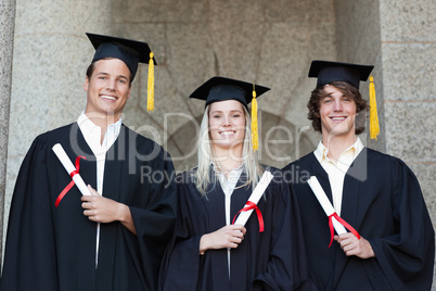 Graduates holding their diploma while posing