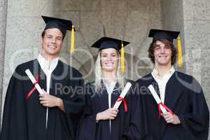 Graduates holding their diploma while posing
