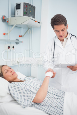 Doctor looking at his chart while holding hand of his patient