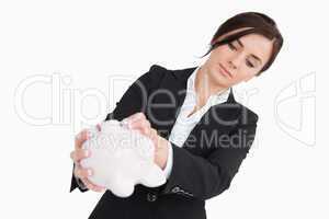 Young woman in suit emptying a piggy bank