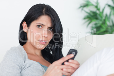 Woman holding a phone while relaxing on a sofa