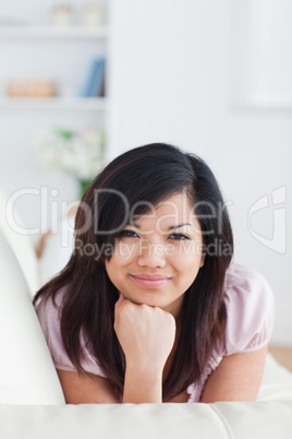 Smiling woman lying on a couch while holding her head with her f