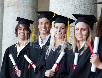 Portrait of smiling graduates posing in single line