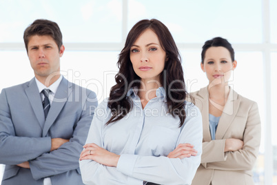 Three serious business people crossing their arms in a well-lit