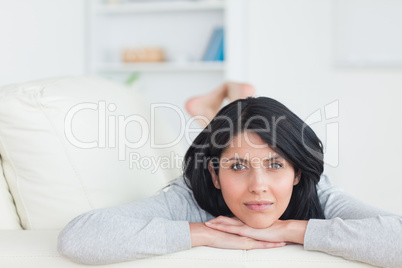 Woman resting on a couch and holding her head with two hands
