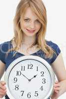 Woman holding a clock while looking at camera