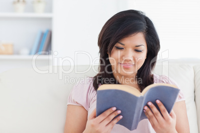 Woman sitting on a sofa while reading a book