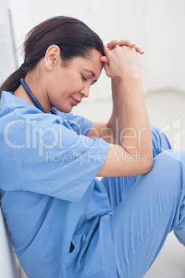Nurse sitting on the floor with her head on her hands
