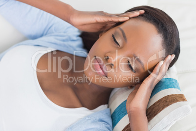 Black woman lying while having hands on temples