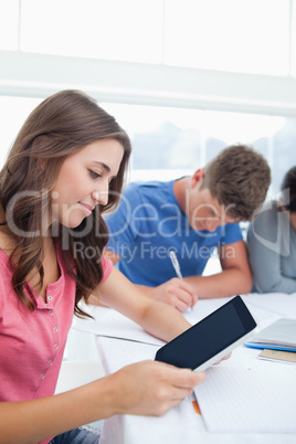 A woman looking at her tablet while studying