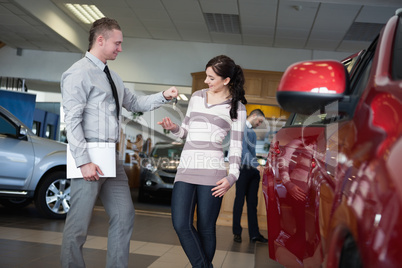 Salesman giving car keys to a woman