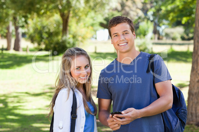 Portrait of a student showing his smartphone screen to a girl