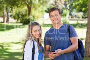 Portrait of a student showing his smartphone screen to a girl