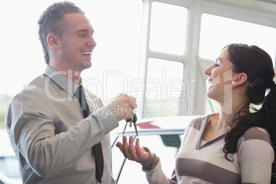 Laughing salesman giving keys to a woman