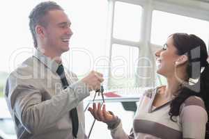 Laughing salesman giving keys to a woman
