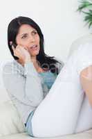 Woman talking on the phone while relaxing on a sofa